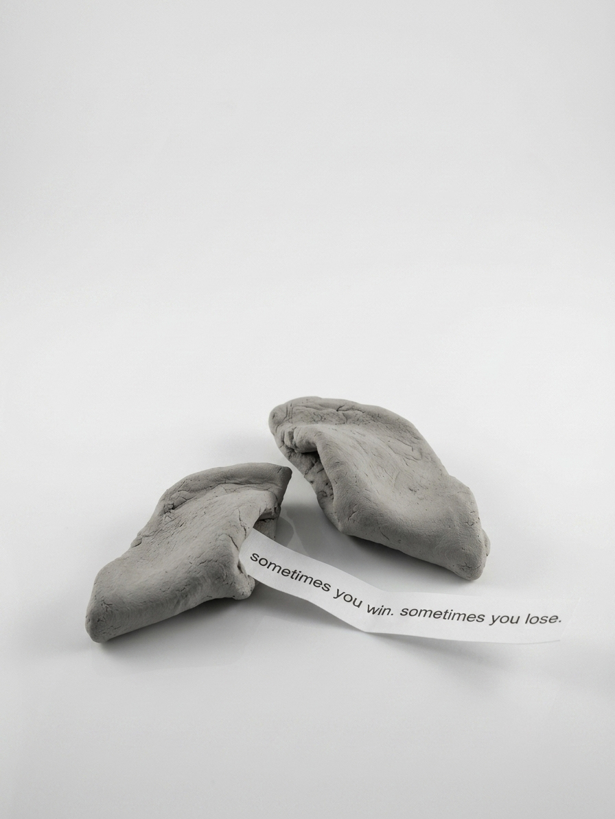 SOMETIMES — a fortune cookie cast in clay, cracked open, the slip reading: sometimes you win. sometimes you lose.